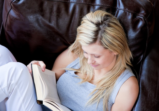 ソファーで本を読んでいる愉快な女性