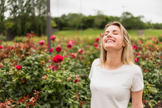 Donna allegra che sta in giardino floreale