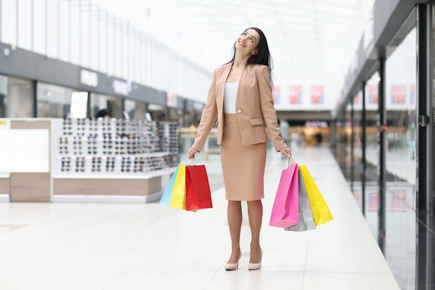 Joyful woman stands in mall with paper shopping bags