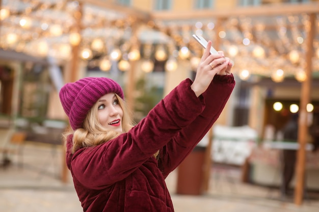 Joyful woman taking selfie at the street with garlands