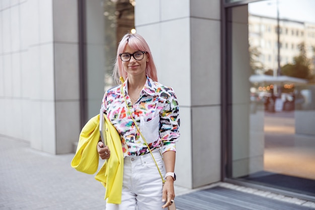 Joyful woman with laptop standing on the street