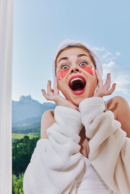 Joyful woman with patches on her face against the background of nature mountains on the balcony