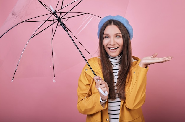 Joyful woman in yellow rain jacket with umbrella laughs