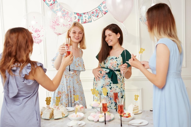 A joyful women celebrating together during the genre reveal the party over balloons background