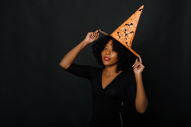 Joyful young black woman with afro haircut wearing a Halloween hat