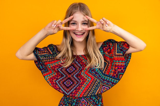 Joyful young blonde slavic girl gesturing victory sign