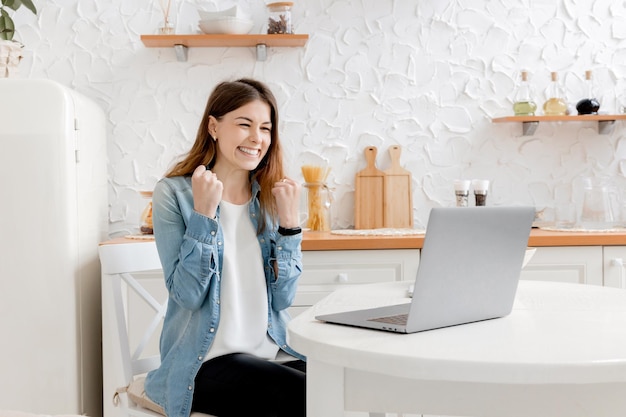 Joyful young business woman is happy about her work achievement
smiling looking at laptop