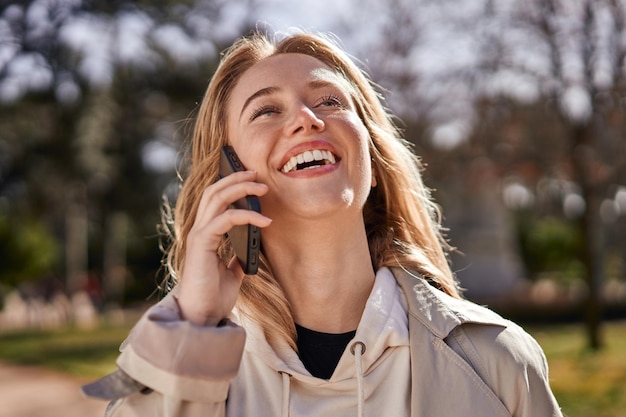 Joyful young Caucasian woman talking on phone