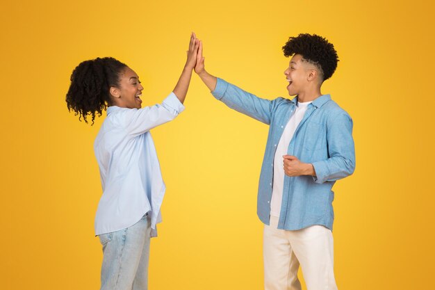 Joyful young couple celebrating success with a high five smiling and laughing together