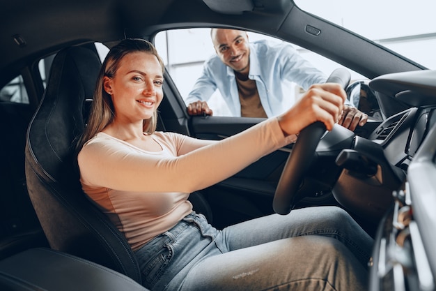 Gioiosa coppia giovane guardandosi intorno all'interno di una nuova automobile