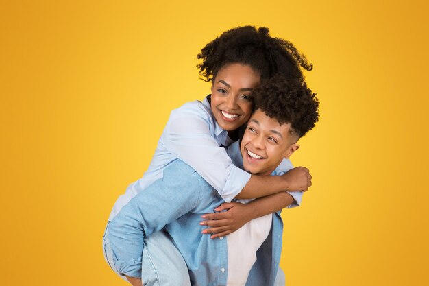 Joyful young couple sharing a piggyback ride with the woman embracing the man