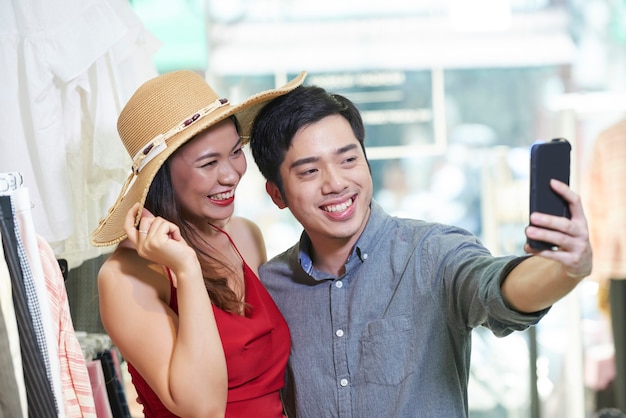 Joyful young couple taking selfie in department store when shopping together