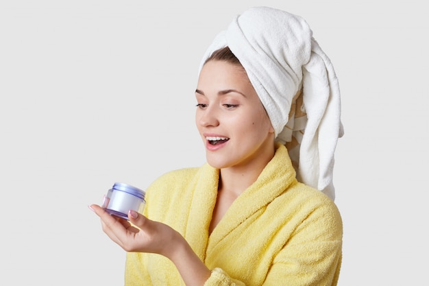 Joyful young European woman holds bottle with cream