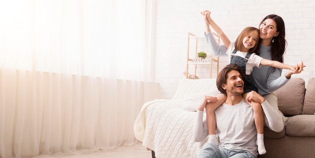 喜び の ある 3 人 の 若い 家族 が 家 で 一緒 に ふざけ て 楽しん で いる