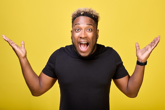 Joyful young guy of pleasant appearance spread his hands gratefully to sides