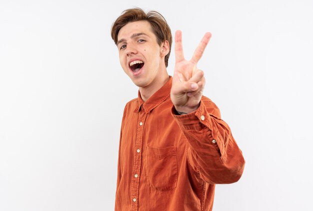 Радостный молодой красивый парень в красной рубашке показывает жест мира