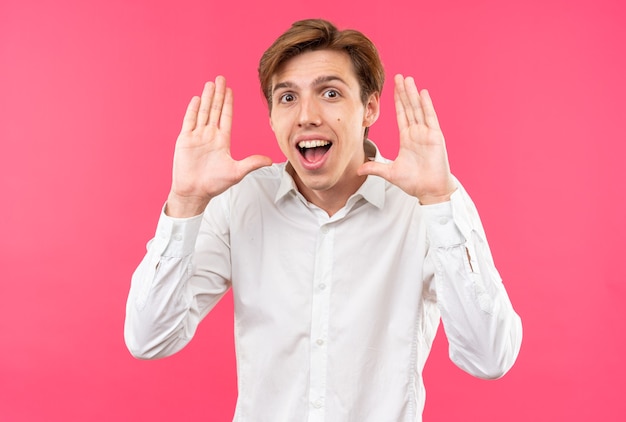 Joyful young handsome guy wearing white shirt showing stop gesture 