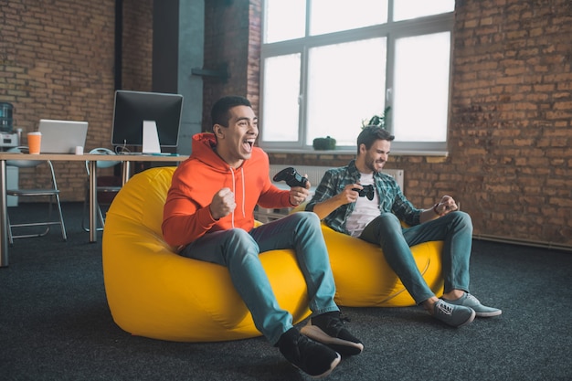 Joyful young man holding a game console while expressing his happiness from winning the game