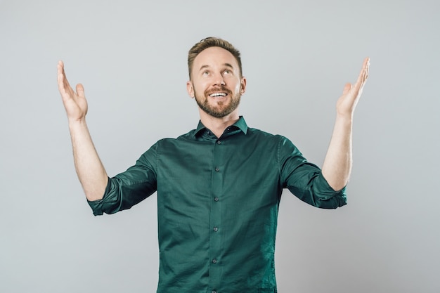 Joyful young man raising arms and looking up