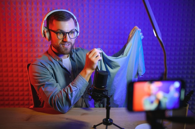 Joyful young man recording unboxing video in studio