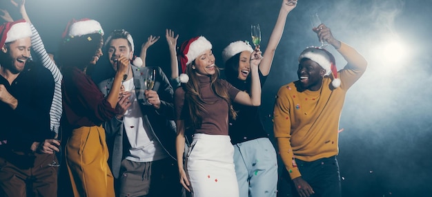 Foto giovani gioiosi che ballano e brindano con lo champagne mentre si godono la festa di capodanno in un night club