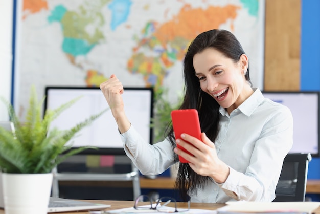 Joyful young woman in euphoria looks at smartphone screen