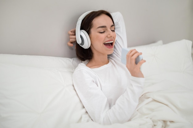 Joyful young woman having fun in bed at home