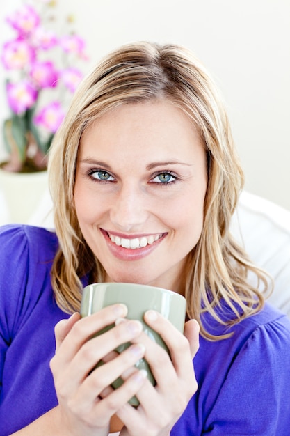 Фото Радостная молодая женщина с чашкой кофе на диване