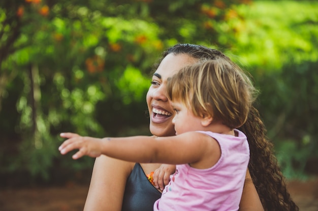 Радостная молодая женщина и маленький милый ребенок девочка, указывая в парке