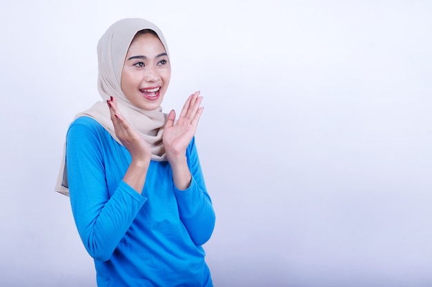 Joyful young woman with blue t-shirt wearing hijab surprising expression