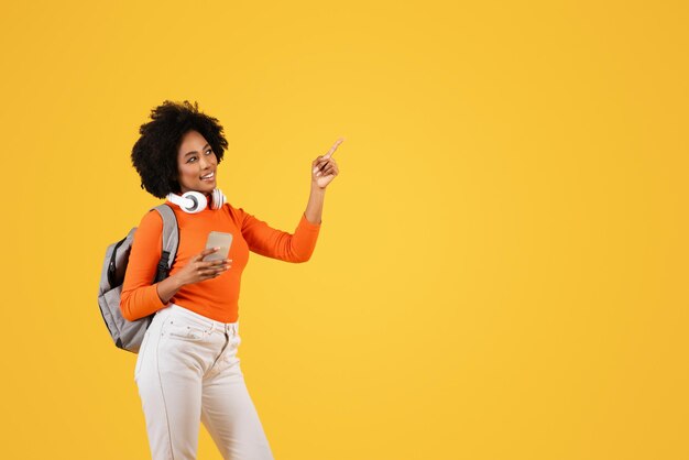 A joyful young woman with curly hair wearing a bright orange shirt white pants