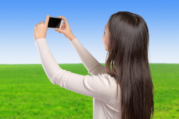 彼女のスマートフォンでselfieを作るうれしそうな若い女性