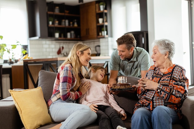 Joyous Family Celebrating Grandmothers Birthday With Cake in a Cozy Living Room