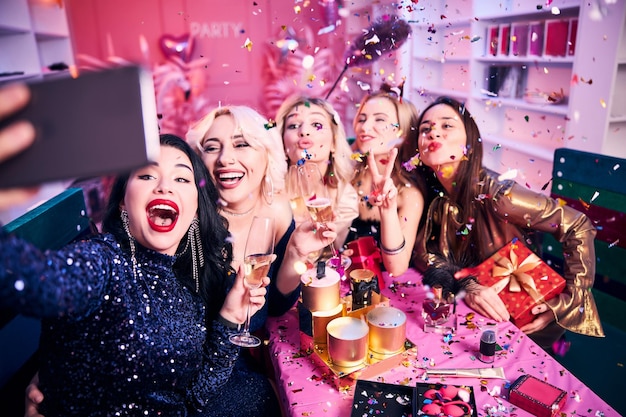 Joyous female colleagues photographing themselves at the festive table