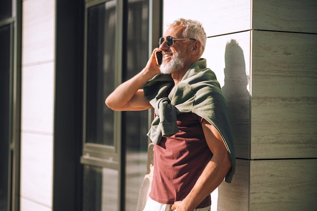 Joyous male talking on the smartphone outside