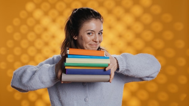 Joyous person walking with pile of novels feeling delighted studio background