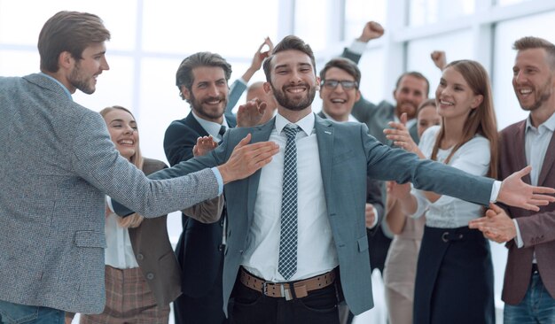 Jubelende jonge zakenman die de felicitaties van zijn zakelijke team accepteert