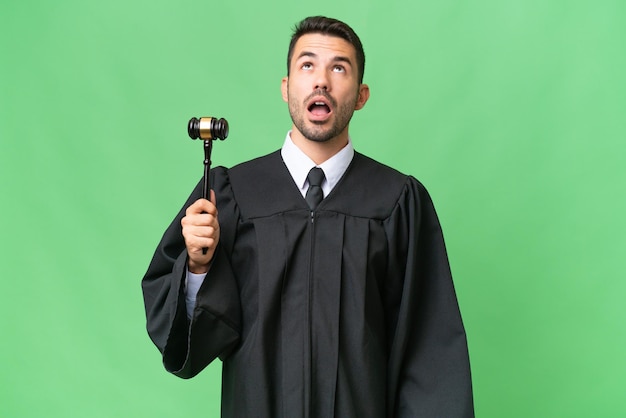 Judge caucasian man over isolated background looking up and with surprised expression