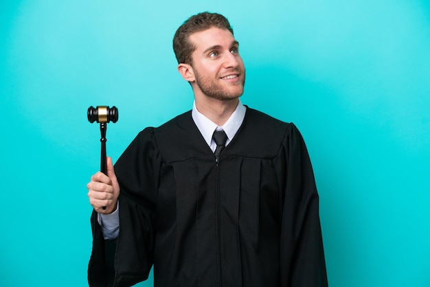 Foto giudice uomo caucasico isolato su sfondo blu pensando a un'idea mentre guarda in alto