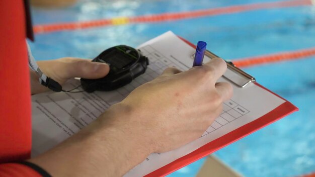 Judge at competition in pool closeup of the judges hand in the pool which records the testimony in