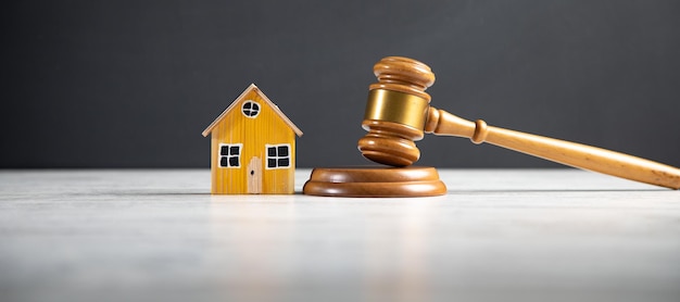 Молоток судьи и модель дома в зале суда, закон о недвижимости и аукционе собственности conceptxDxA