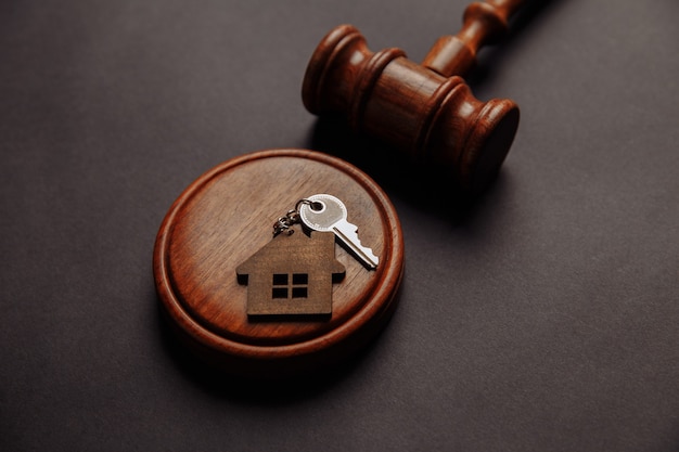 Judge gavel and key chain in shape of two splited part of house on wooden