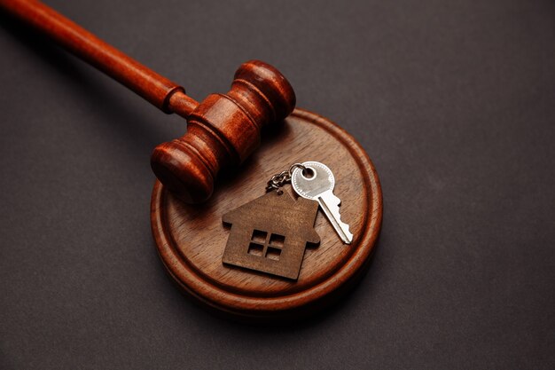 Judge gavel and key chain in shape of two splited part of house on wooden