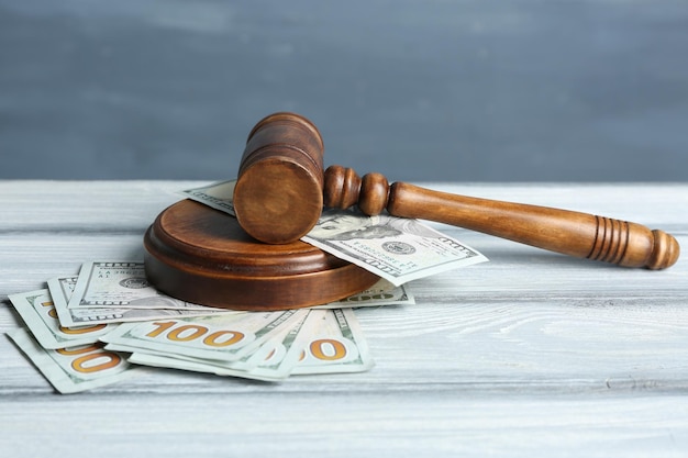 Judge gavel and money on wooden table against color background