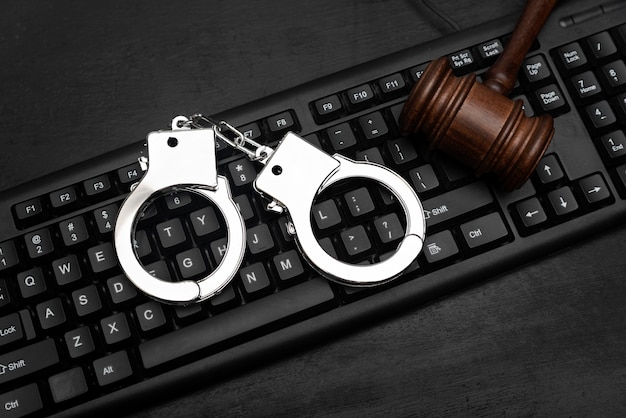 Photo judge gavel and police handcuffs on computer keyboard. cyber crime concept. online piracy.