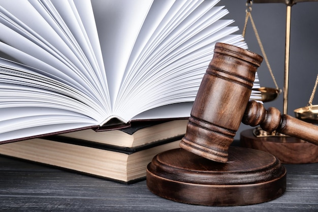 Judge gavel scales and books on wooden table closeup
