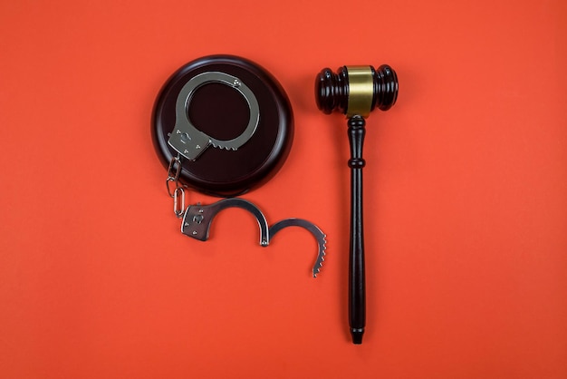 Photo judge gavel with handcuffs on orange background