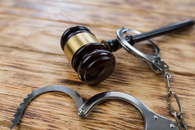 Photo judge gavel with handcuffs on wooden background