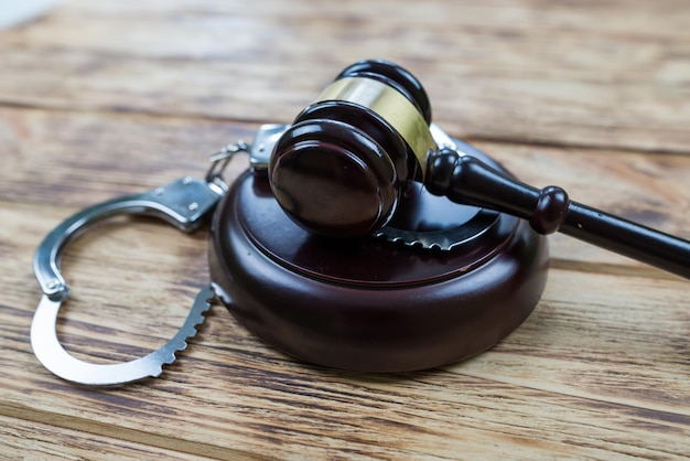 Judge gavel with handcuffs on wooden background