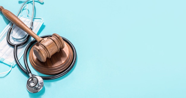 Judge gavel with medical mask and stethoscope on blue background Protection of medical rights concept